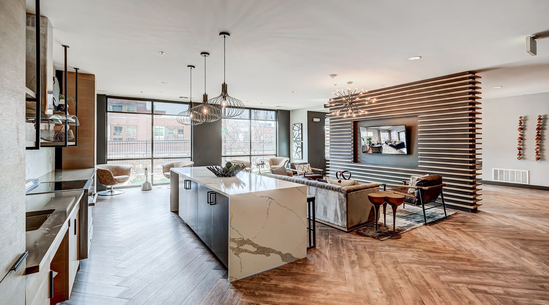a room with a kitchen island, large windows,and a tv